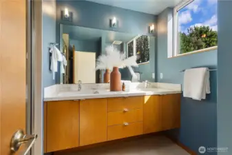Roomy primary bathroom has dual sinks and concrete counters and cabinets to match the kitchen.