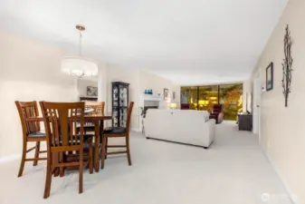 View of dining and living spaces with gas fireplace and floor-to-ceiling glass.