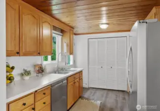 Galley style kitchen with stainless steel appliances, laundry closet, backyard facing sink window and door to backyard patio.