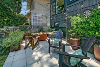 The patio is shaded by a legacy cedar tree.