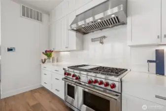 At the heart of the kitchen, a Wolf dual-fuel six-burner range with griddle and double oven is paired with a Best variable-speed hood and blower—crafted for serious cooking and effortless entertaining.