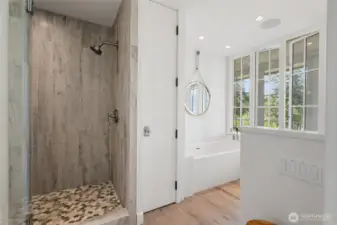 A spa-inspired bath with tiled walk-in shower and BainUltra “City” spa tub, all framed by serene water views.