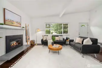 Step into the light & bright vaulted living room with wood beam accent, large front window, and fireplace with sitting ledge.