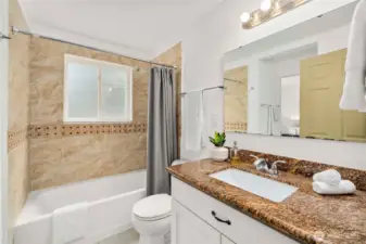 Full bathroom in granite & tile, includes direct access to primary bedroom opposite the sink.