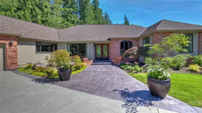 Inviting front entry features stamped concrete, brick monument posts, and handsome wood double doors accented with leaded glass. The basalt column water feature provides soothing background sounds.