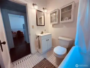 Main bathroom with fresher vanity, tile floors, and claw foot tub.