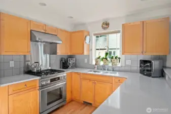 Kitchen features quartz counters, tile backsplash & stainless appliances.