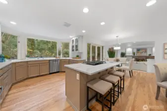 Completely remodeled kitchen featuring quartz countertops, a generous center island with seating, updated fixtures, and beautifully refinished hardwood floors—designed for both function and style.