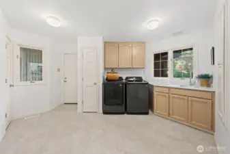 Spacious main-level utility room featuring washer and dryer, upon request, abundant cabinetry, and a convenient sink—designed for everyday functionality and easy household organization.The door to the left leads you to the three car-garage.