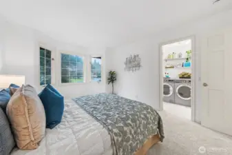 Bedroom Two features new carpet and fresh paint, with peaceful window views that fill the room with natural light. Enjoy convenient access to the upper-level laundry area (virtually staged for illustration). Note the solid wood six-panel door, a quality detail found throughout the home.