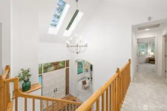 Light-filled upper landing with skylights, an elegant chandelier, and classic wood railings—creating an open, airy transition between bedrooms and living spaces.