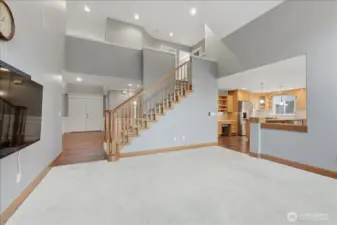 Opposite view of family room towards the front door, staircase and kitchen. (TV and sound bar will convey.)