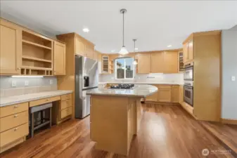 Kitchen with S/S appliances, granite island cooktop, planning desk and a walk-in pantry.