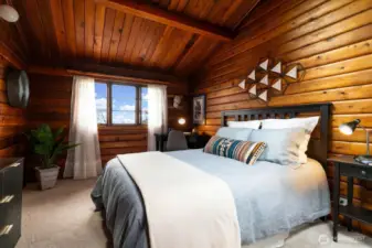 Space for a queen-sized bed and dresser in this main floor bedroom with vaulted ceiling and large west-facing view window