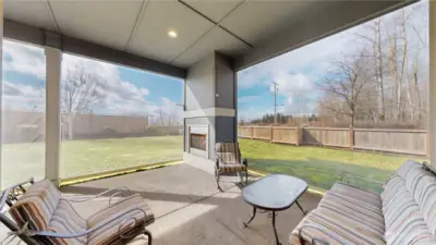 Covered patio with privacy screens, outdoor fireplace, and mountain view backdrop.