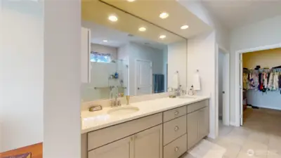 Primary bath with dual-sink vanity, glass-enclosed shower, and walk-in closet