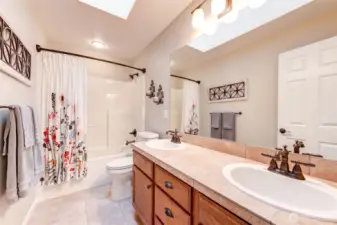 “Upstairs guest bath with dual vanity and skylight, providing both function and natural light.”