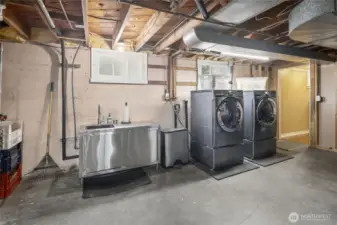 Downstairs laundry room with sink and stairs to back patio