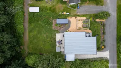 Aerial view of property showing house, vegetable garden, storage container, and alley access to back of property.