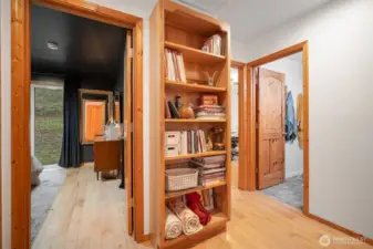 As you leave the main part of the home, you'll see the built-in custom cabinetry for additional storage (another storage area just across the bookcase--not int the picture) plus access to both bedrooms, a large utility room, and a bathroom.