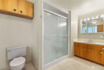 Bathroom in primary suite has large walk in shower with grab bars, large vanity and tile floors.