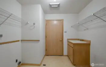 Spacious laundry, sink cupboard, hanging rack.