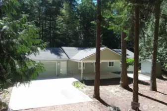 Front of house. One level living. Large parking pad goes to the oversized garage (26 feet w by 26 feet depth). The covered carport allows extra parking as well as a pass-through area for a circular driveway.