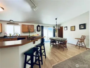 View from hallway towards kitchen, dining room and mud/ laundry room beyond, sliding glass door to back patio and garden boxes