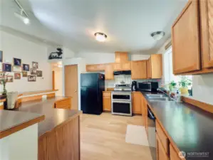 View of kitchen from dining room: island, double oven, refrigerator and dishwasher stay with home