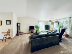 View of living room from hallway, lots of light from the two large windows, entryway to the right