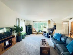 Living room with large windows looking out toward fruit tree orchard