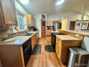 Easy maintenance glass stove top, plenty of cabinets and counter tops and a pantry right through the door in the center of this photo. The other side of the island on the right is breakfast bar dining space. The living room is just beyond the island. The dining room table and the door out to the deck is just behind this spot.