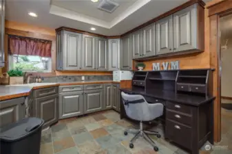 A study with a coved ceiling and extensive counter work space and storage cabinets, a jetted sink, and an in-wall ironing board.  Also potentially a second laundry room, as all hook-ups are present.