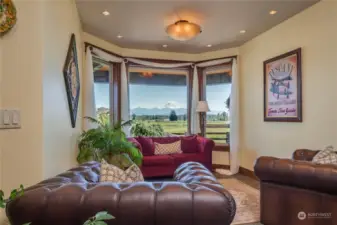 A sitting room with bay windows and a superb mountain view; notice the central light fixture surrounded by recessed can lighting