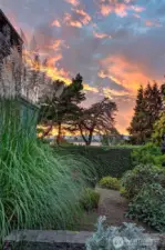 At day’s end, the west garden glows. Grasses, conifers, and flowering shrubs rise in layered rhythm beneath a sky streaked with salmon and gold. Tucked just beyond the Dining Room and Living Room, this private landscape invites quiet contemplation and connection to the timeless drama of light, weather, and season.