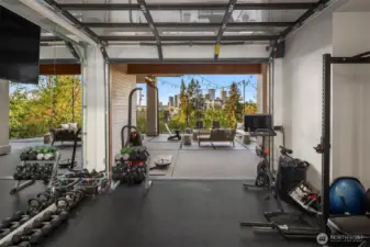 This home gym is an awesome place to work out with a roll up garage door to showcase the stunning views and floor to ceiling mirrored wall to assist with your workouts.