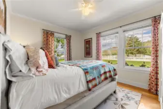 Sunny main floor bedroom with hardwood floors and double-pane windows framing pastoral views—offering comfort, quiet, and a daily dose of countryside charm.