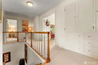 Upper landing with charming built-in cabinetry and elegant wood railings that add a graceful touch to the stairwell—an inviting space connecting light-filled bedrooms and the top deck beyond.