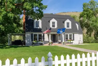 Classic 1930s farmhouse with fresh exterior paint, charming dormers, and a brand-new roof—timeless style and modern care in a serene, tree-lined setting.