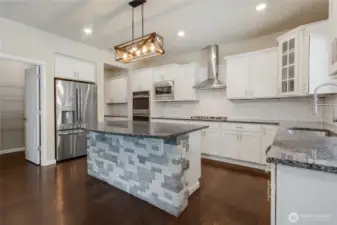 Kitchen island has a stone front that matches the fireplace. Large walk in pantry by fridge.