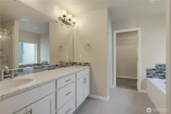 Nice size primary bathrrom w/quartz counter, dual sinks, soaker tub & tile floor.  Walk in closet straight ahead