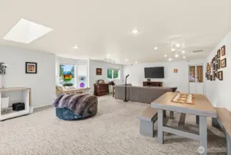 This large gathering media room is perfect for movie nights, gaming, and crafting activities, offering a versatile space for family and friends. A bay window fills the room with natural light and provides a cozy nook for reading or relaxing, while a skylight enhances the airy, open feel. A sliding glass door opens to a deck, ideal for outdoor lounging, and a nearby door leads directly to the inground pool area, creating easy access for poolside fun and entertainment. The room's layout makes it a great hub for both indoor and outdoor activities.            This large gathering media room is perfect for movie nights, gaming, and crafting activities, offering a versatile space for family and friends. A bay window fills the room with natural light and provides a cozy nook for reading or relaxing, while a skylight enhances the airy, open feel. A sliding glass door opens to a deck, ideal for outdoor lounging, and a nearby door leads directly to the inground pool area.