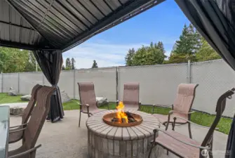 The outdoor entertaining area features a covered gazebo, complete with comfortable seating, perfect for hosting gatherings in any weather. Nestled nearby is a cozy firepit, ideal for evening conversations and roasting marshmallows under the stars.