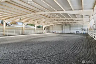 80 x 150 clear span steel construction, it offers sand and ground rubber footing for optimal traction and comfort. Entrance doors at both ends provide easy access, while vapor lighting ensures excellent visibility. The arena is equipped with a sprinkler system to minimize dust, and the interior walls are finished with vinyl fencing, enhancing both safety and aesthetics.