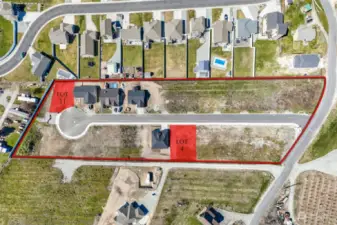 Top down aerial of community with available lot markers in red.