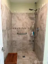 Large walk-in shower with beautiful decorative tile. Multi-head shower.