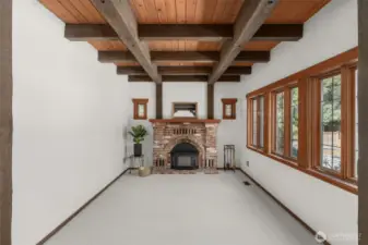 Wood beams and a living room anchored with a cozy fireplace.