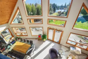 25’ view window-wall with wood-wrapped windows overlooking picturesque yard and Trout Lake views  Lake-facing glass French doors