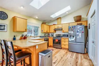 Stainless steel appliances and plenty of cabinet storage. More skylights and a pantry on the right.