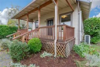 HUGE covered front porch looks out at lovingly curated foliage in fully fenced yard.